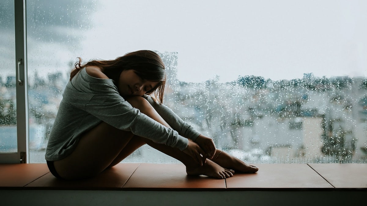 woman in gray long sleeve shirt sitting on window